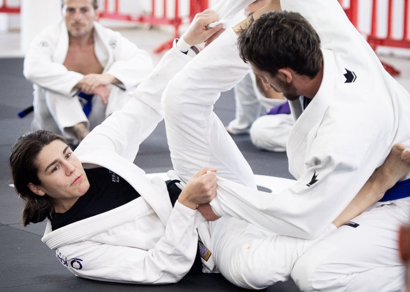 Students drilling Brazilian jiu jitsu in white BJJ gis on the mats